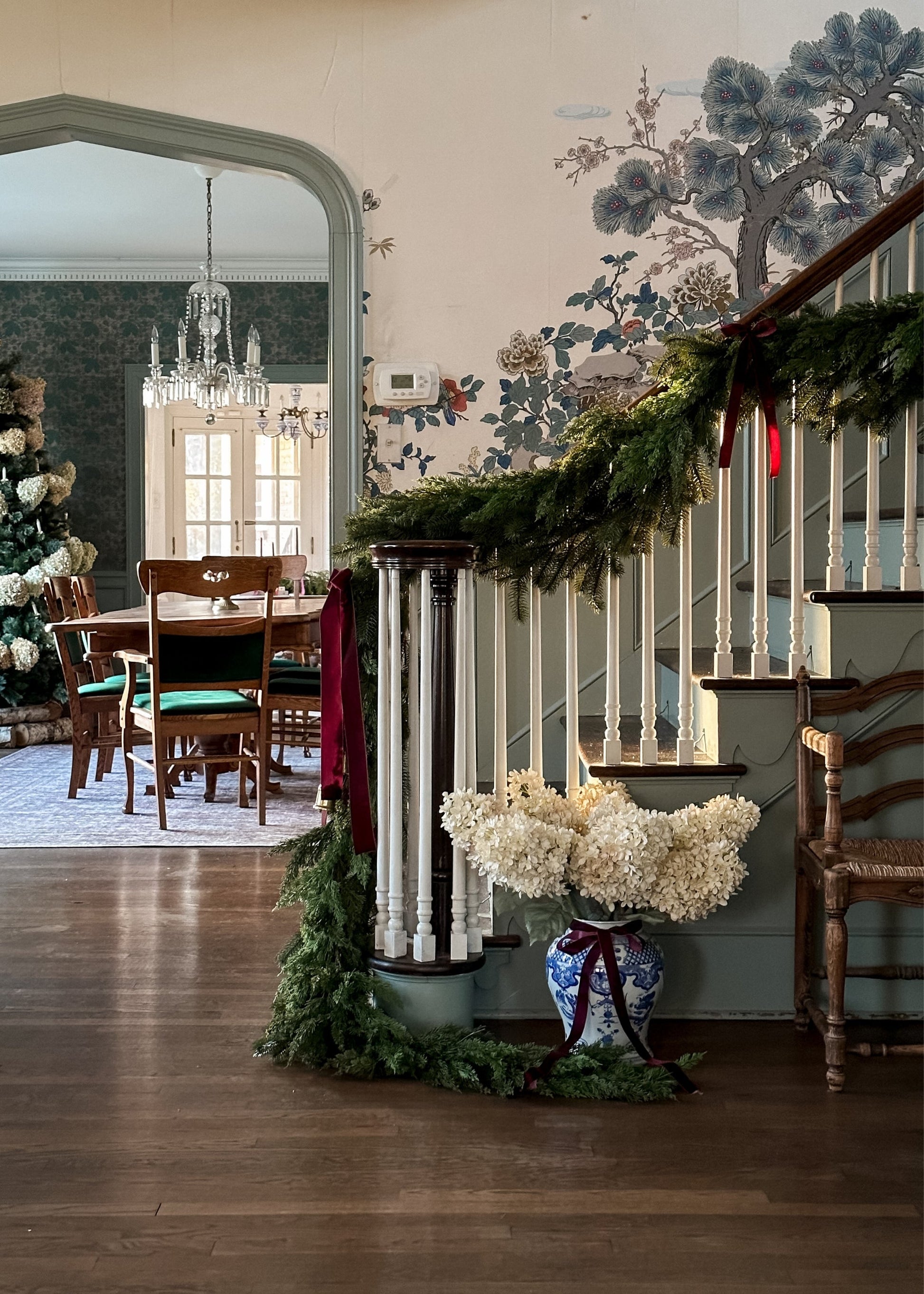 Decorative staircase with cedar greenery garalnd and a vase of parchment hydrangeas in a home 
interior.