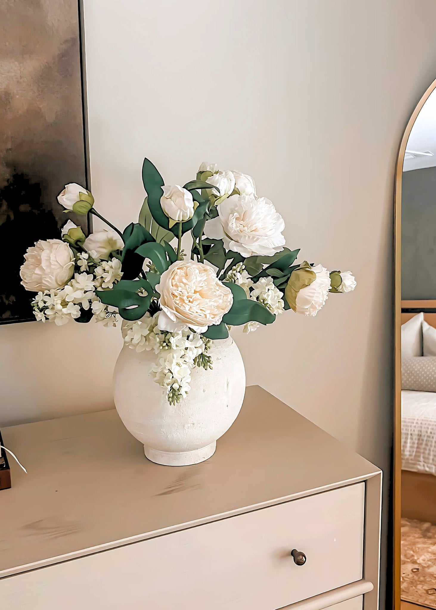 White vase with faux peony flowers on a dresser 